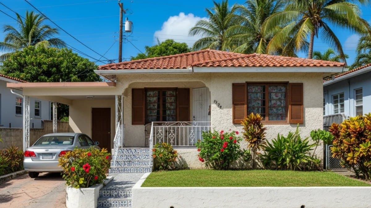 Casa puertorriqueña con marquesina y un patio de grama verde y bien cuidada bajo el sol